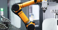 A bright yellow robotic arm appears in a manufacturing facility.