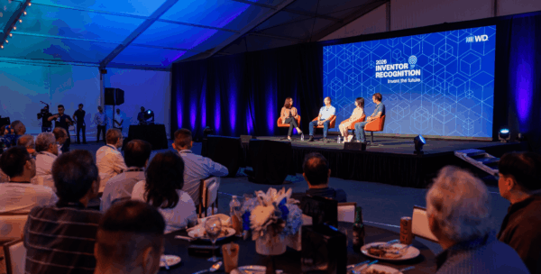 Panel discussion on stage at WD Elevate 2026 with four speakers and audience seated at tables, discussing inventor recognition and innovation culture.